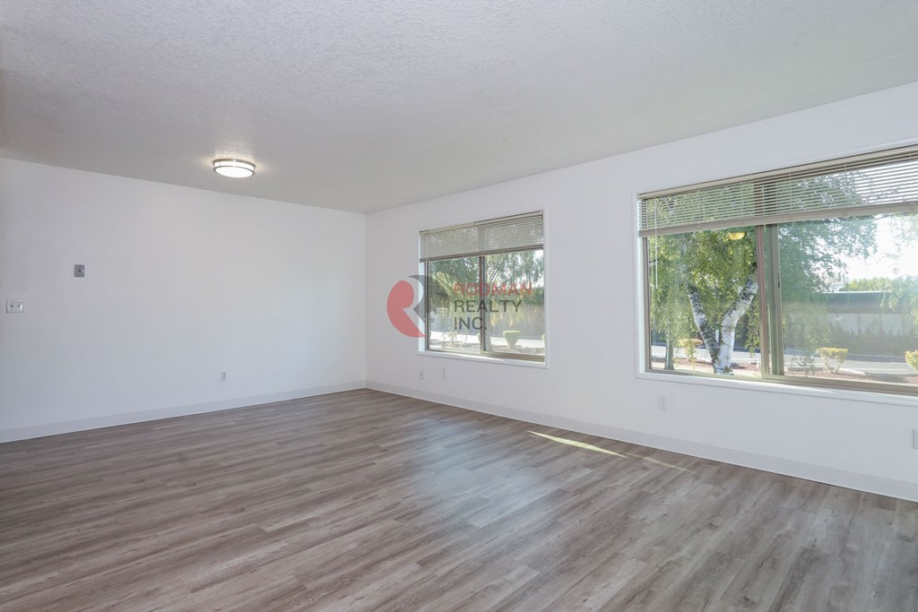 Empty room with wooden floor and windows.