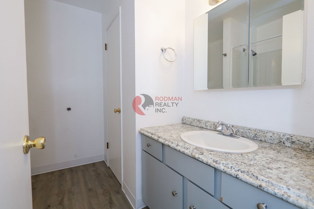 A bathroom with a sink, mirror, and Rodman Realty Inc. logo.