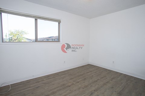 A room with a large window and a logo for Rodman Realty Inc. on the wall.