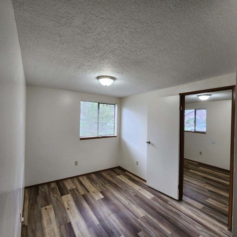 A room with wooden floors and a window with blinds.