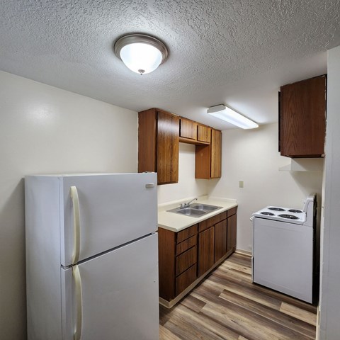 A small kitchen with a white refrigerator and a white stove.