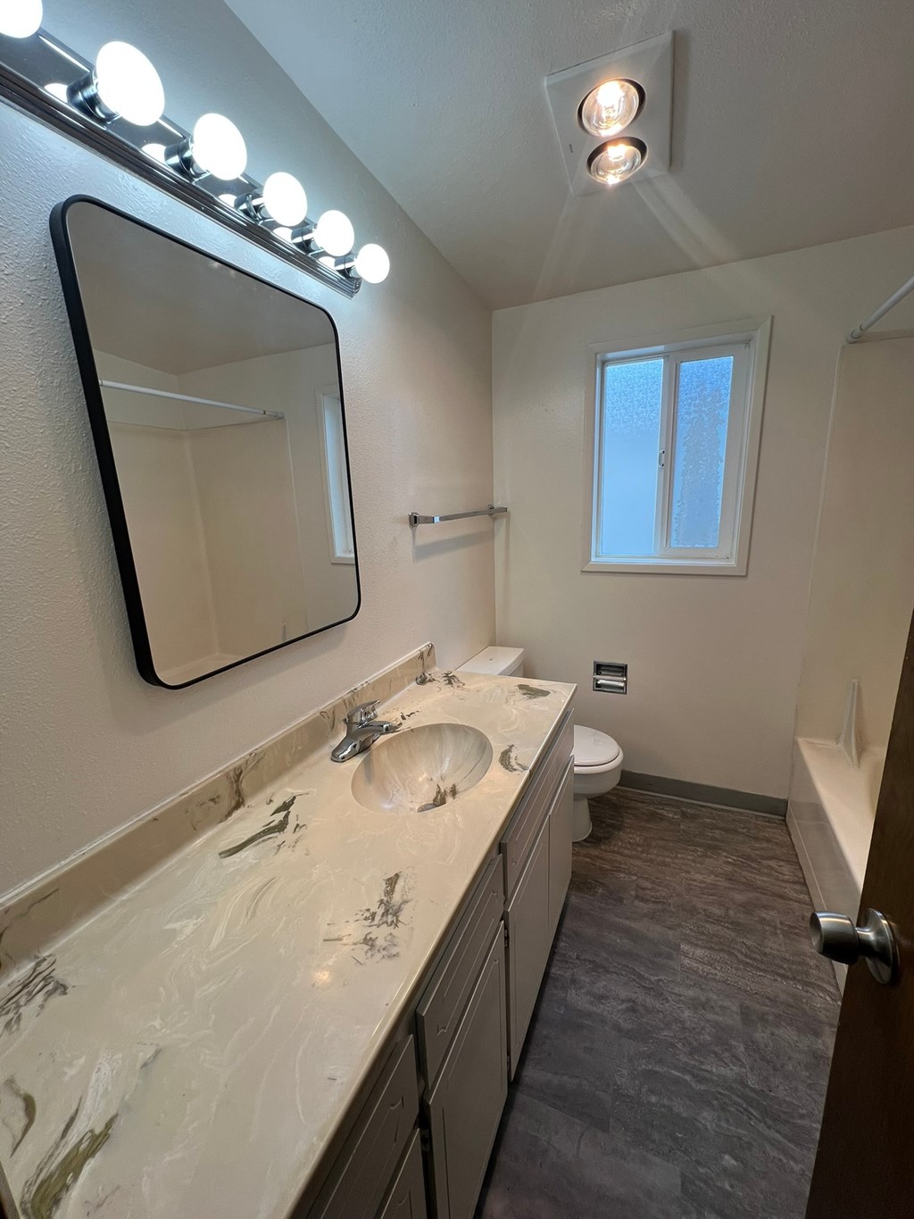 A bathroom with a sink, mirror, and lights.