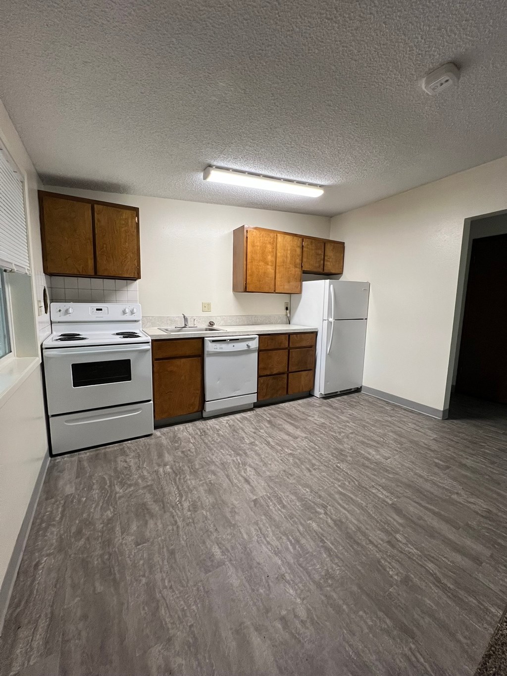 A kitchen with white appliances and wooden cabinets.