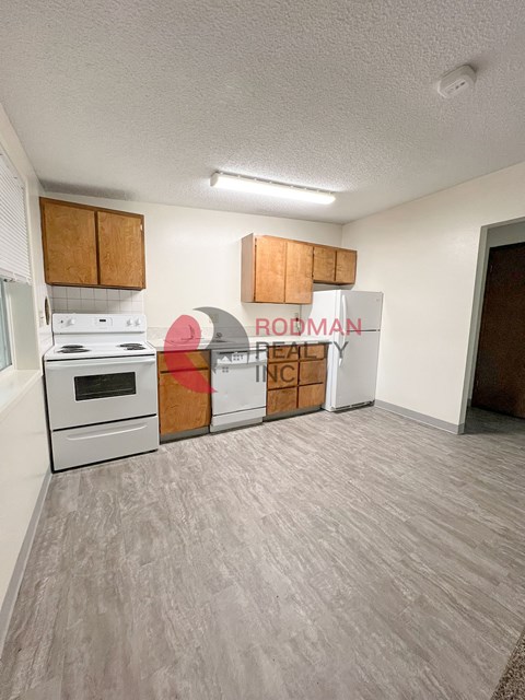 A room with a white stove and wooden cabinets.