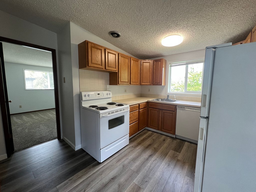 A kitchen with white appliances and wooden cabinets.