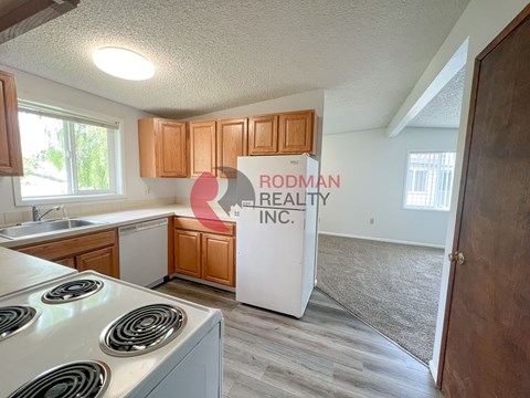 A kitchen with a stove top oven and wooden cabinets.