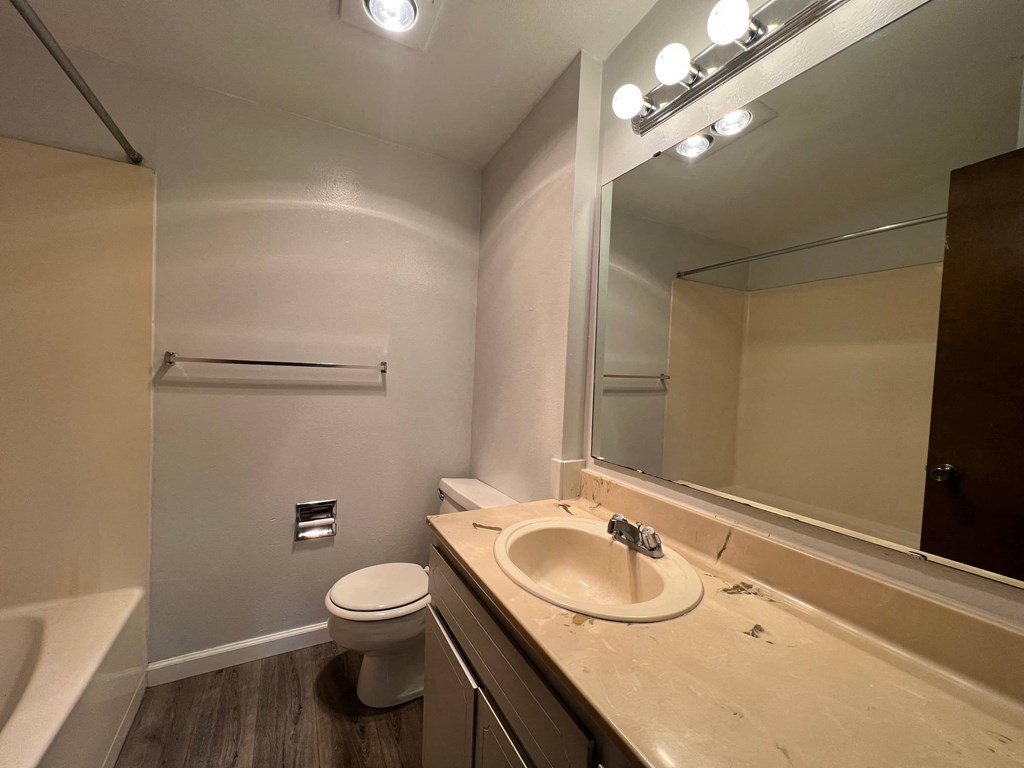 A bathroom with a toilet, sink, and mirror.