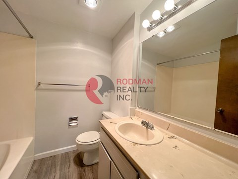 A bathroom with a sink, toilet, and mirror.