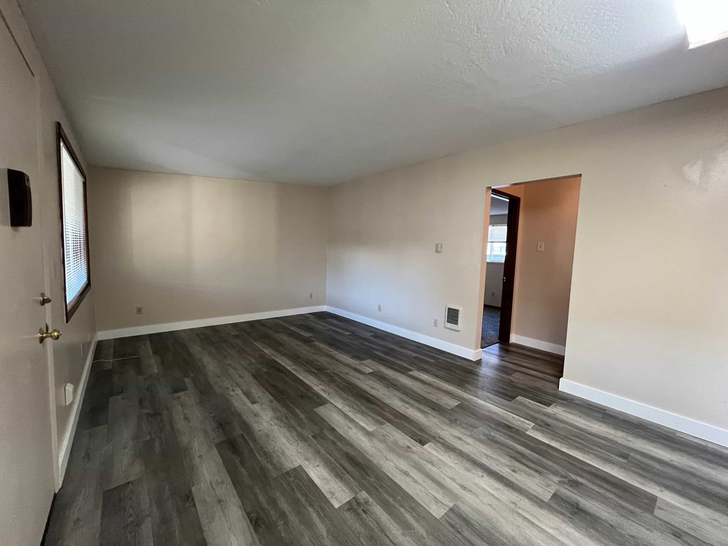 A room with wooden flooring and a door on the right side.