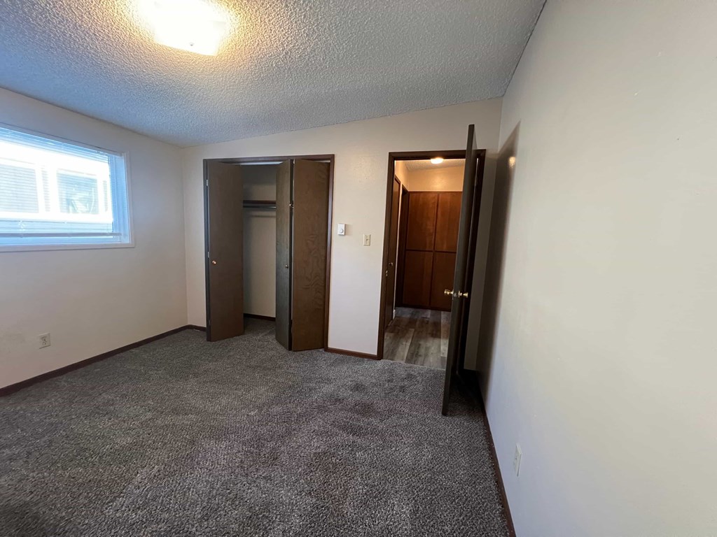 A room with a carpeted floor and two doors.