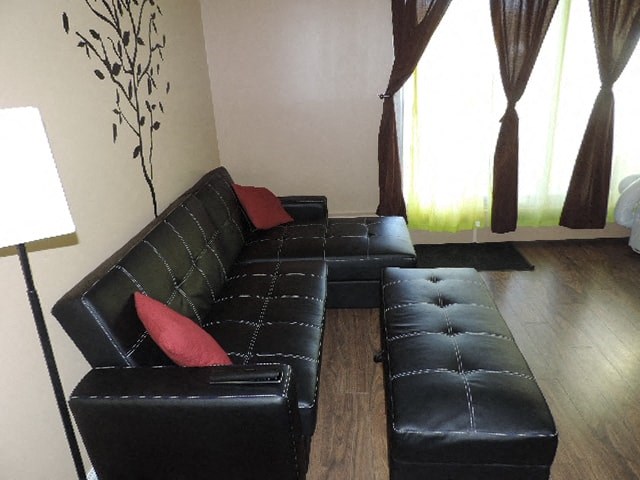 a living room with black leather furniture and a red pillow