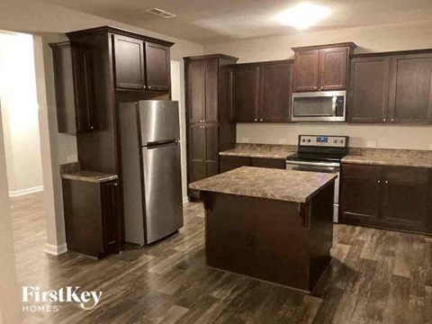 A kitchen with dark wood cabinets and a granite countertop.