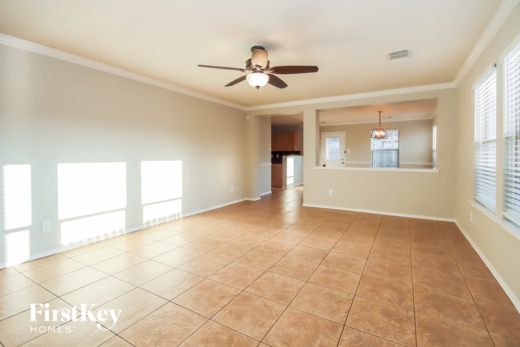 an empty living room with a ceiling fan and tiled floors
