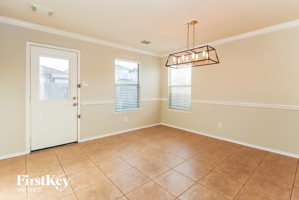 an empty dining room with a door and a light fixture