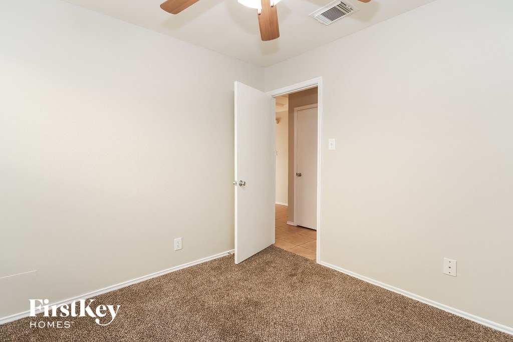 a bedroom with white walls and carpet and a door to a closet