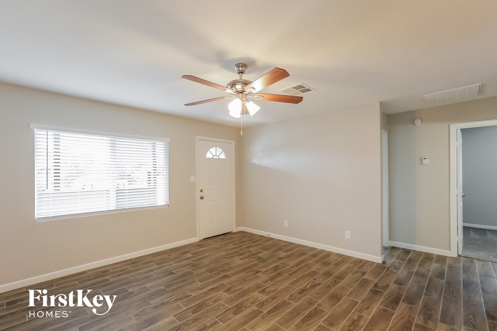 A room with a ceiling fan and wooden flooring.