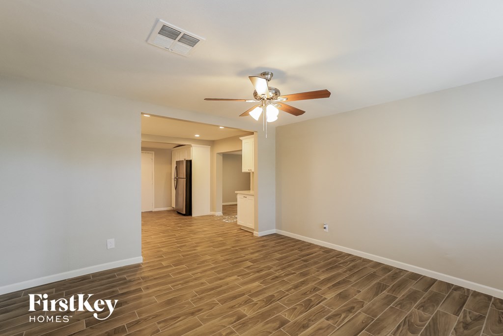 A spacious room with a wood floor and a ceiling fan.