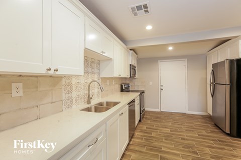 A kitchen with white cabinets and a black refrigerator.