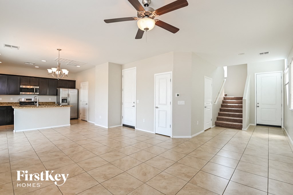 A spacious living room with a kitchen area in the background.