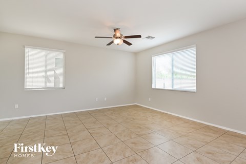 A spacious room with a ceiling fan and two windows.
