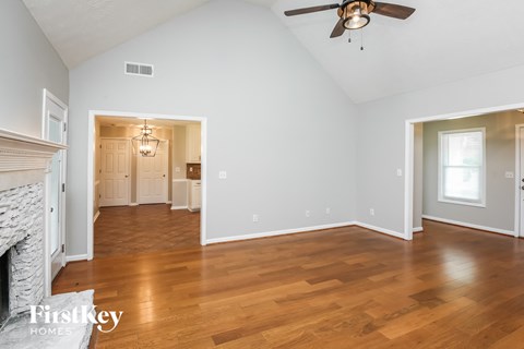 A spacious room with a fireplace and wood flooring.