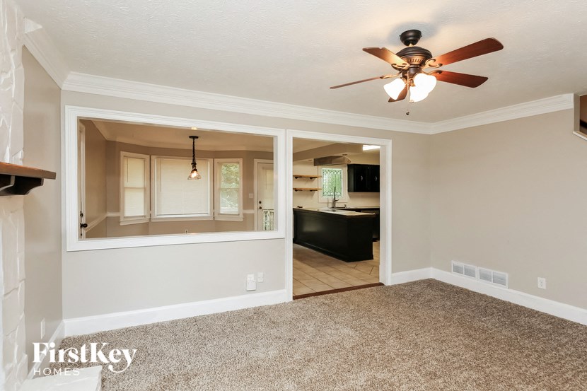 an empty living room and kitchen with a ceiling fan