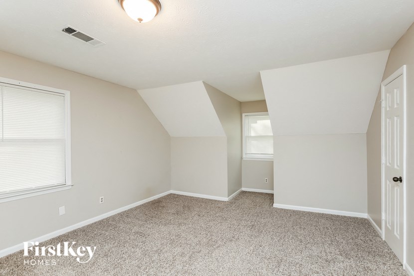 an empty bedroom with carpet and a door to the bathroom