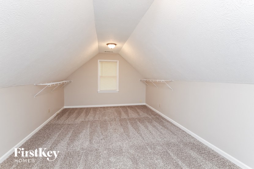 the attic bedroom of a house with white walls and carpet