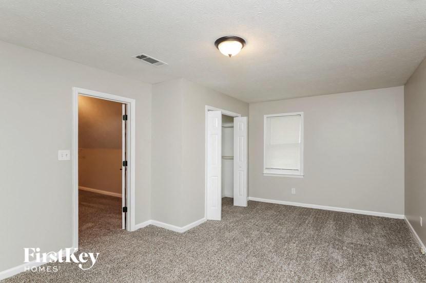 a bedroom with a door to a hallway and a carpeted floor