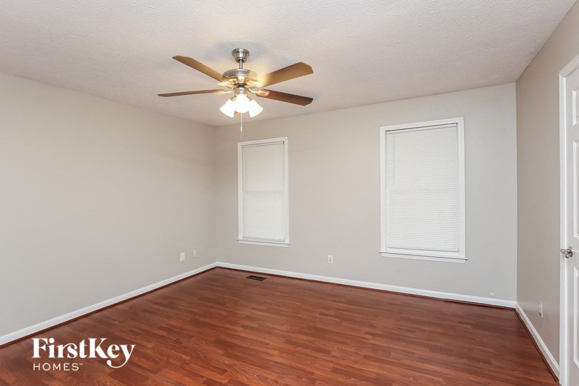 the spacious living room with hardwood flooring and a ceiling fan