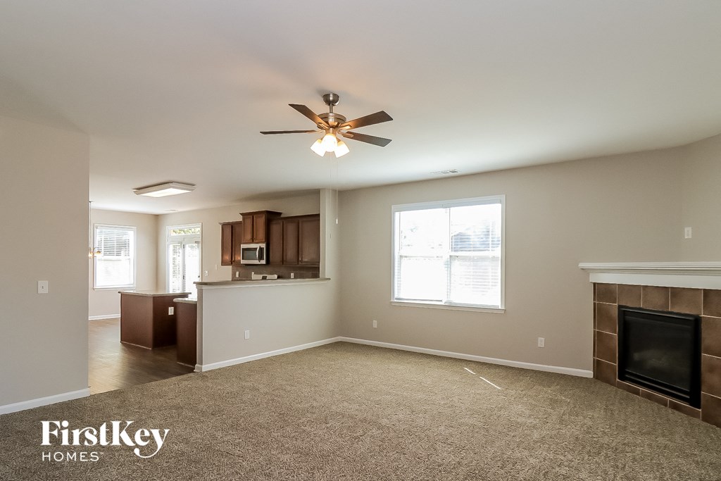 an empty living room with a fireplace and a ceiling fan