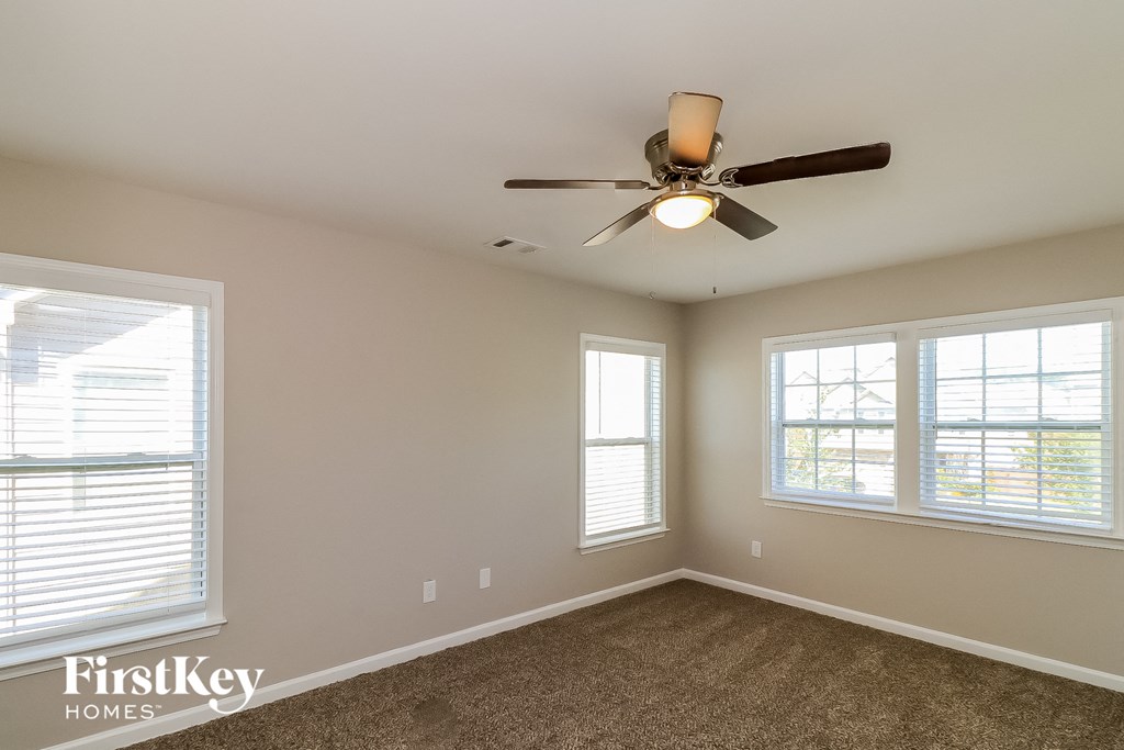 a bedroom with a ceiling fan and three windows