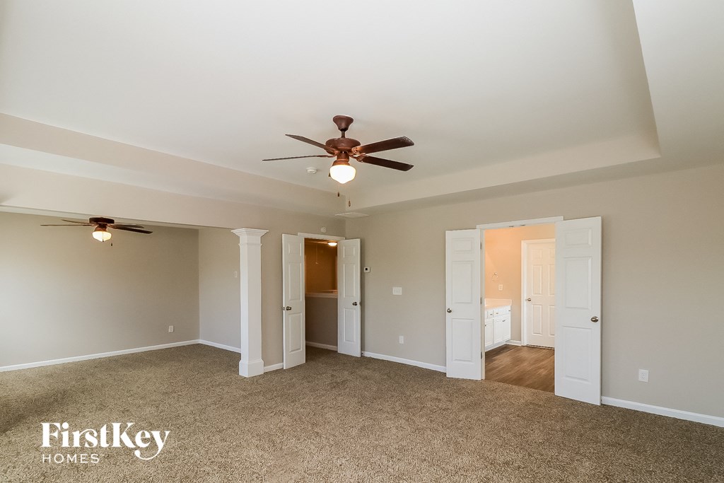 an empty living room with ceiling fan and doorways to different rooms