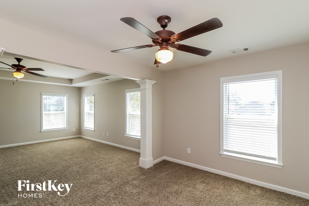 a living room with a ceiling fan and two windows