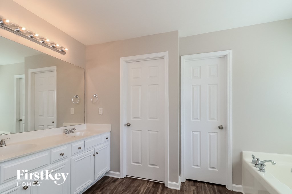a white bathroom with two sinks and two doors