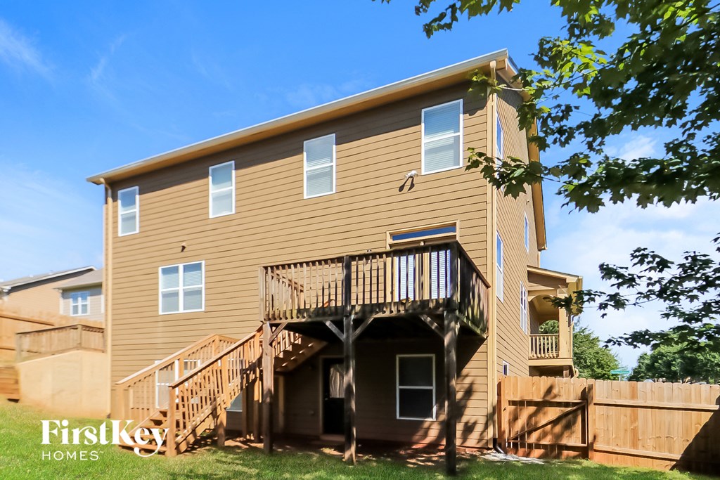 the back of the house with a deck and a wooden fence
