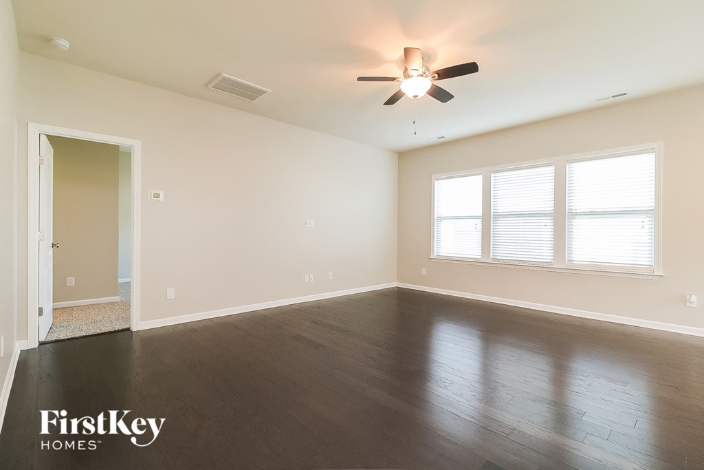 a empty living room with wood floors and a ceiling fan
