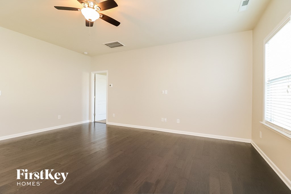 an empty living room with wood floors and a ceiling fan