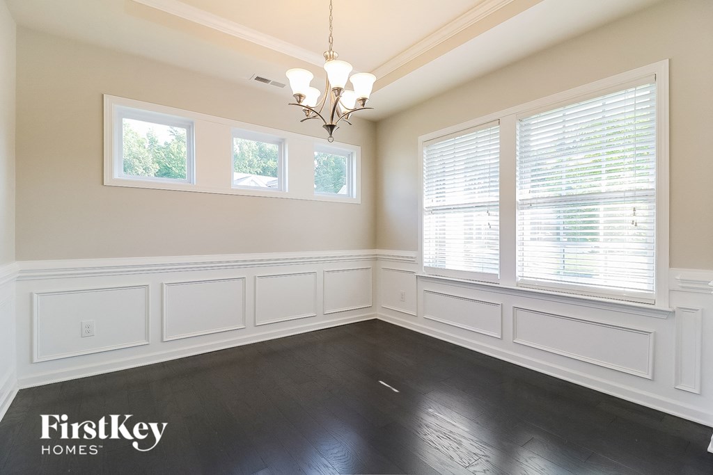 a dining room with white wainscoting and windows