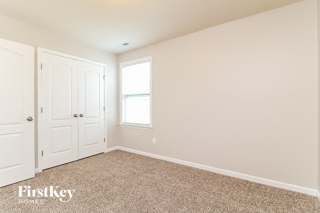 a bedroom with two closets and a window and a carpeted floor