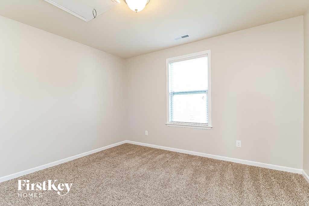 a bedroom with white walls and carpet and a window