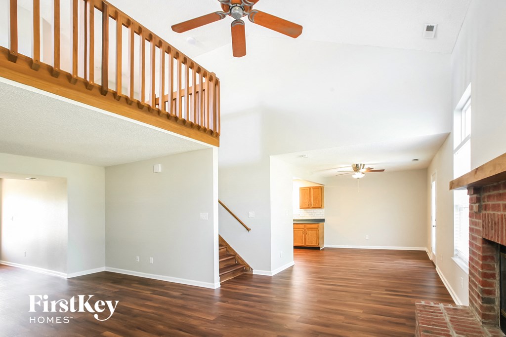 an empty living room with a staircase and a ceiling fan