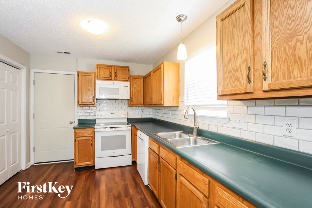 a kitchen with wooden cabinets and white appliances and a green counter top