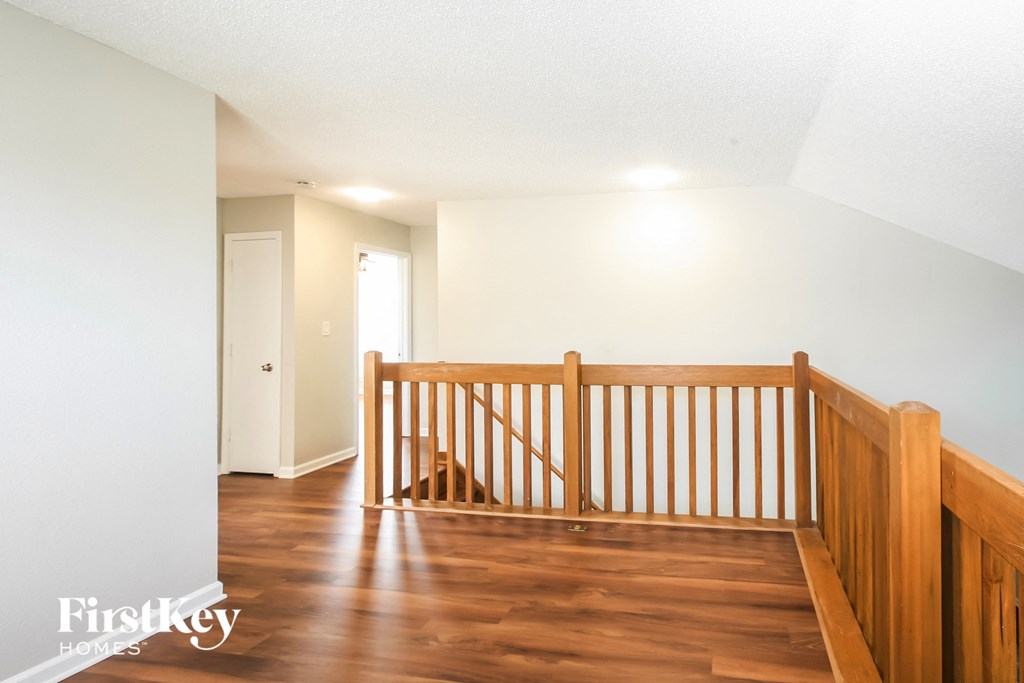 a room with a wooden staircase with a dog on the floor