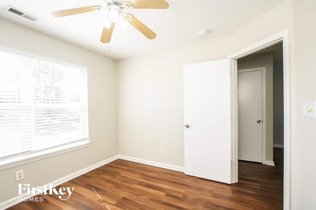 a bedroom with white walls and wood flooring and a ceiling fan