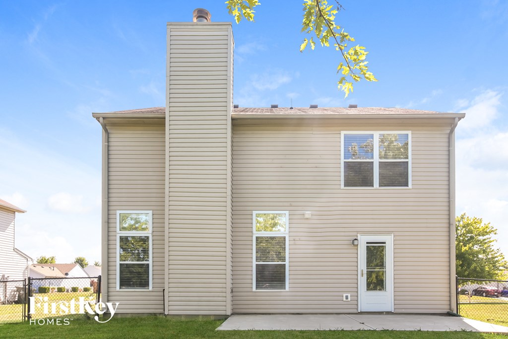 the exterior of a small tan house with two windows and a white door