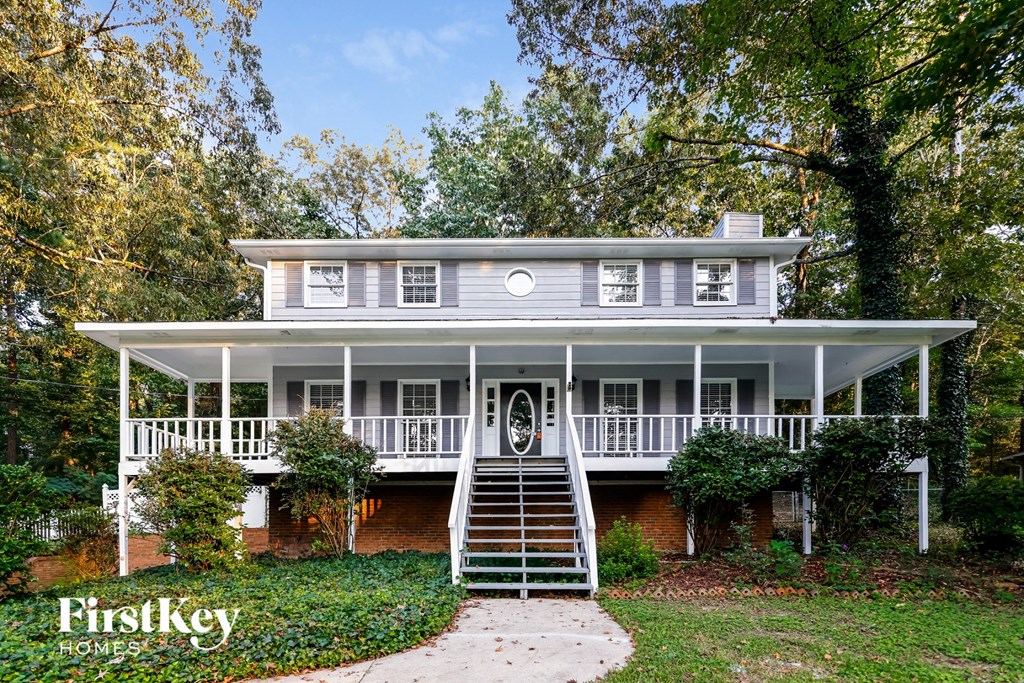 A white house with a porch and a staircase leading to the front door.