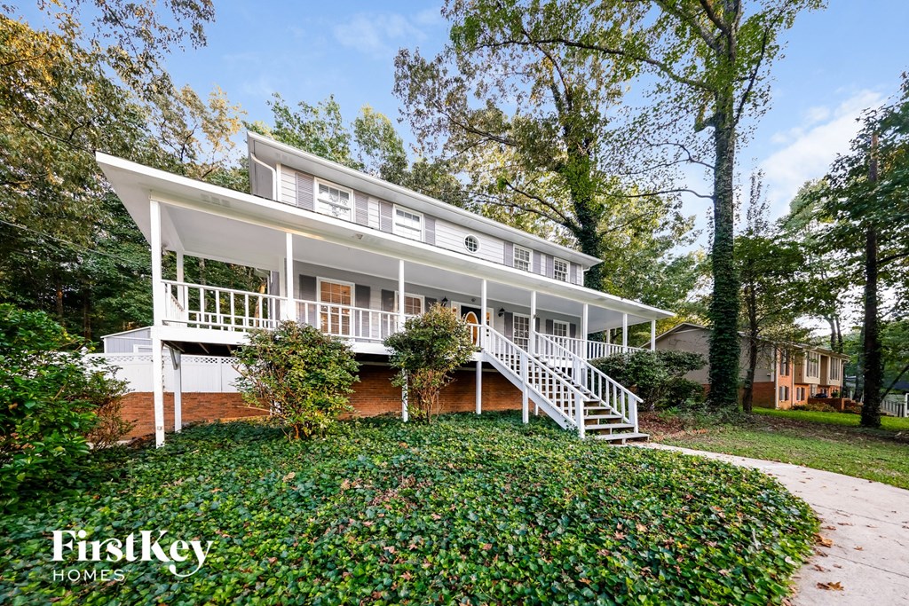 A white house with a porch and a staircase leading to it.