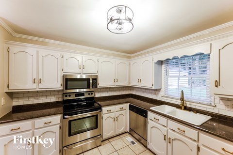A kitchen with white cabinets and a stainless steel oven.