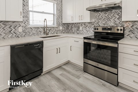 a white kitchen with black appliances and white cabinets